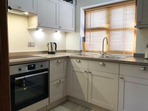 a kitchen with white cabinets and a sink at Garden Cottage in Hasfield