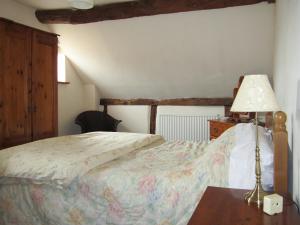 HasfieldにあるGarden Cottageのベッドルーム1室(ベッド1台、テーブルの上にランプ付)