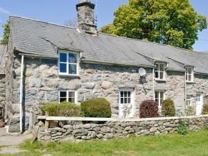 an old stone house with a stone wall at Hen Hafod in Llanfor