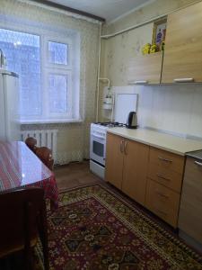 a kitchen with a stove and a table and a window at Однокомнатная Встреча in Astana