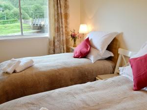 a bedroom with two beds with red and white pillows at Bydand in Walkerburn