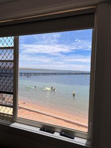 una ventana con vistas a una playa con gente en el agua en Beachside & Jetty View Apartment 5 - Harbour Master Apt, en Streaky Bay