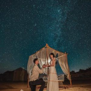 un hombre y una mujer tomados de la mano bajo un paraguas en Desert Lover's Luxury Camp, en Merzouga