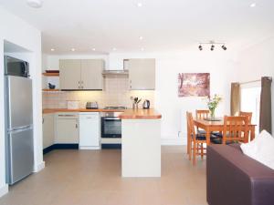 MarldonにあるIvy Cottage - 28150の白いキャビネットとテーブル付きのキッチンが備わります。