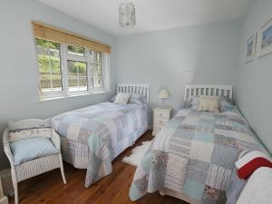 1 dormitorio con 2 camas y ventana en The Retreat Lulworth en West Lulworth