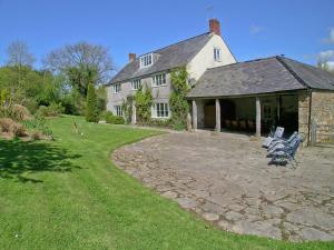 een groot wit huis met een patio ervoor bij Purcombe Farmhouse - 28458 in Whitchurch Canonicorum