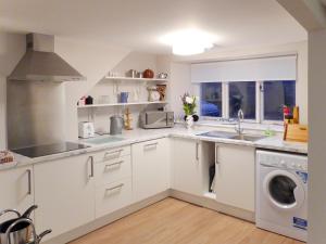 a kitchen with white cabinets and a washer and dryer at The White House in Pitlochry