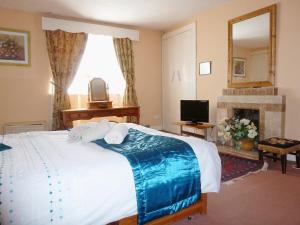 1 dormitorio con cama, TV y chimenea en The White House, en Pitlochry