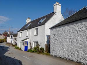 a white brick house with a blue door on a street at The White House in Pitlochry