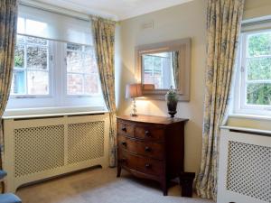 a bedroom with a dresser and two windows at The Coach House in Tattingstone
