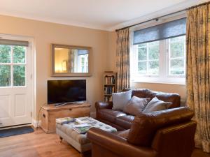 a living room with a leather couch and a television at The Coach House in Tattingstone
