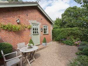 a brick house with a table and a green door at The Coach House in Tattingstone