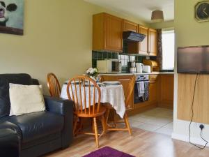 a living room with a table and a kitchen at Pine Cottage in Cote