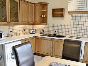 a kitchen with wooden cabinets and a table and chairs at Levans Cottage in Lindale