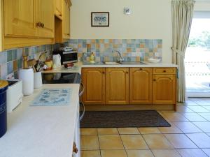 a kitchen with wooden cabinets and a tile floor at Meadow View in Leiston