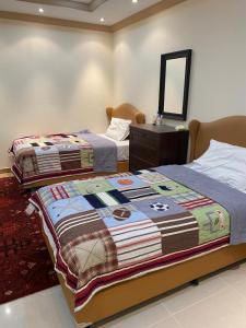 a bedroom with two beds and a dresser and a mirror at شقه مفروشه للايجار اليومي in Mecca