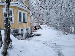 a house with snow on the ground next to it at Sydåbacka Guest House, a Room with a Sauna in Kirkkonummi