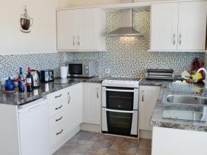 a kitchen with white cabinets and a sink at Winloma in Port William