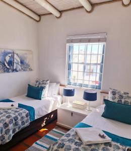 a bedroom with two beds and a window at Flamink Beach View Cottage in Paternoster in Paternoster