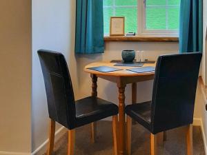 a wooden table with two black chairs and a window at Forge Cottage - 28221 in Shaldon