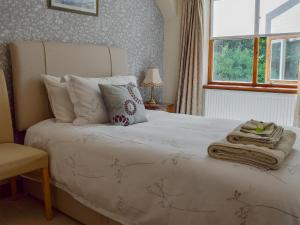 a bedroom with a large white bed with a window at Russet Cottage in Moreton in Marsh