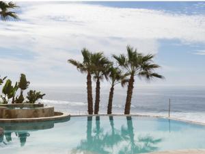 een zwembad met palmbomen en de oceaan bij Azure Rosarito Rental in Rosarito