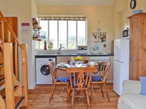 a kitchen with a table and chairs in a kitchen at Russett Cottage-19745 in Peasmarsh