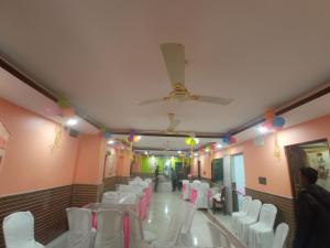 um salão de banquetes com cadeiras e mesas brancas e um tecto em Airport Lodge em Siliguri
