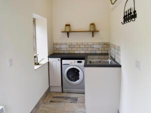a laundry room with a washing machine and a sink at Whatley Lodge in Winsham