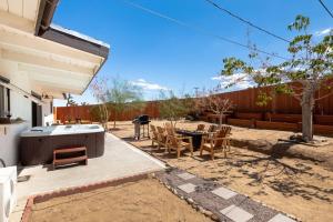 a backyard with a hot tub and a table and chairs at 2 Min To Dt, Fire Pit, Hot Tub, Fully Fenced in Joshua Tree