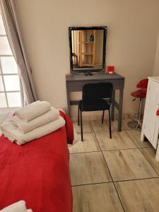 een slaapkamer met een bureau, een stoel en een spiegel bij De Heide Guesthouse in Bothaville