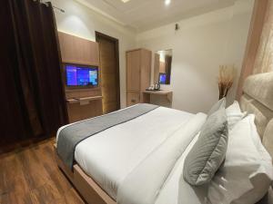 Schlafzimmer mit einem weißen Bett und einem TV in der Unterkunft Hotel Crown Savoy, Near Railway Station & GURU NANAK DEV UNIVERSITY in Amritsar