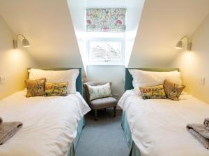 two beds in a room with a window and a chair at Abbeygate House in York