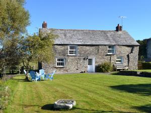 a stone house with chairs and a table in the yard at Nan-tis in St. Issey