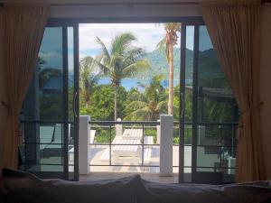 a bedroom with a view of the ocean and palm trees at Villa Seaview Garden in Koh Tao