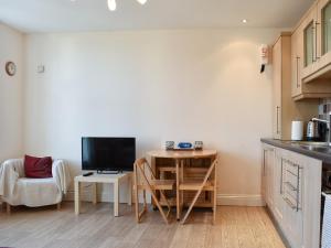 a kitchen with a small table with a tv and a desk at Pinecliffe Avenue in Southbourne