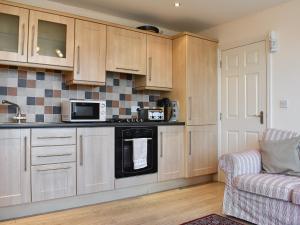 a kitchen with wooden cabinets and a microwave and a couch at Pinecliffe Avenue in Southbourne