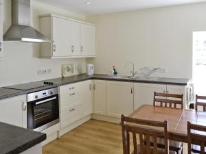 una cocina con armarios blancos y una mesa con sillas. en Diggers Cottage en Oxton