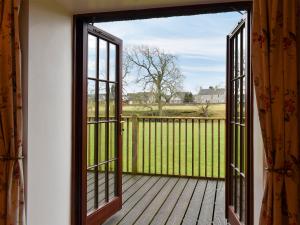 una puerta abierta a una terraza con una valla en Diggers Cottage en Oxton