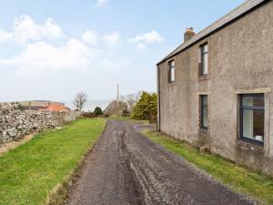 an empty dirt road next to a stone building at Catch A Penny in Burnmouth