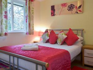 a bedroom with a bed with red pillows and a window at Heligan - B6522 in Saint Cleer
