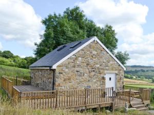 un pequeño edificio de piedra con una valla de madera en Chestnut Cottage en Knitsley