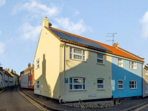 a white house with an orange roof on a street at Leeward Cottage in Wells next the Sea