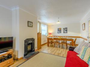 a living room with a red couch and a fireplace at Leeward Cottage in Wells next the Sea