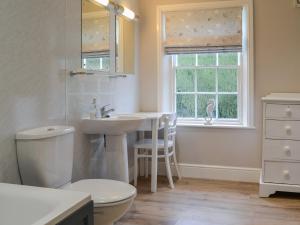 a bathroom with a sink and a toilet and a window at Laundry Cottage in Rudston