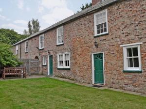 um edifício de tijolos com uma porta verde e um banco em Laundry Cottage em Rudston