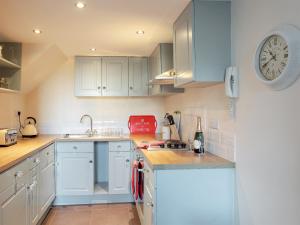 a kitchen with blue cabinets and a clock on the wall at County House Apartment - 27911 in York