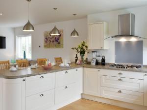 a kitchen with white cabinets and a counter top at Grove Cottage in Newchurch