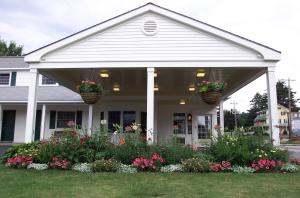 une maison avec 2 paniers de fleurs sur la terrasse couverte à l'avant dans l'établissement Briarcliff Motel, à North Conway