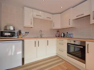 a kitchen with white cabinets and a microwave at Platform One in Paignton